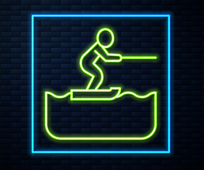Glowing neon line Water skiing man icon isolated on brick wall background. Vector