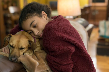 Biracial eleven year-old girl embracing a small brown dog
