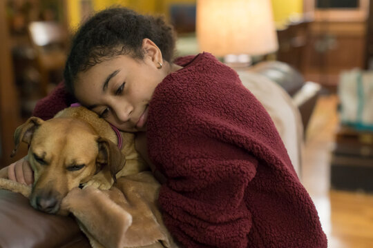 Biracial eleven year-old girl embracing a small brown dog - Powered by Adobe