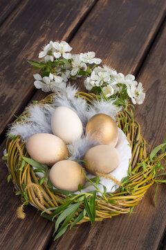 Eggs painted gold in the nest, on the wooden table to celebrate
