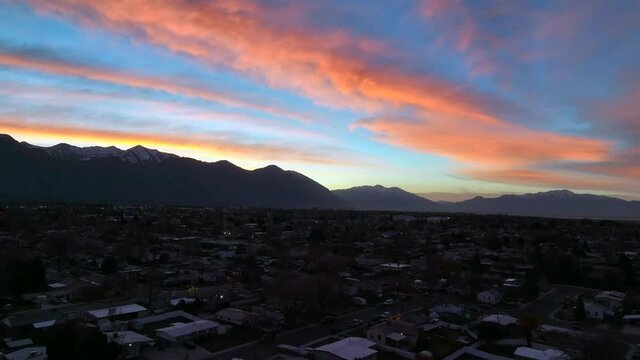 Drone flying over city in the rocky mountains during a beautiful sunrise