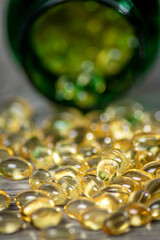 Close Up of a Bottle of Vitamin Gel Capsules Spill Across Grey Board Table