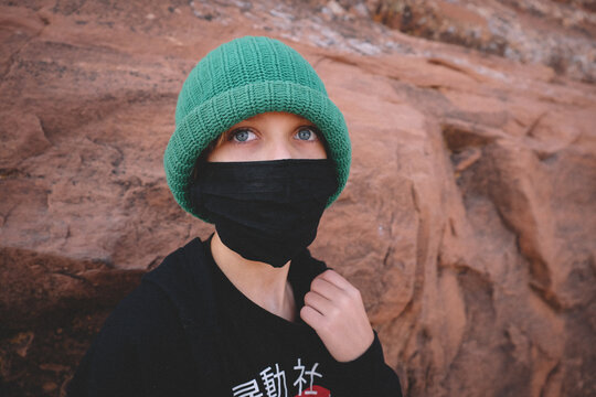 Boy with Big Blue Eyes Peeks from Behind a Mask.