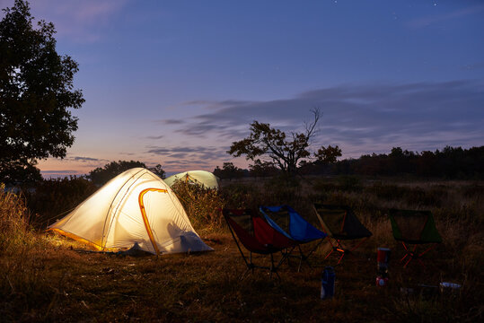Lit up backpacking tents in field just before sunrise.