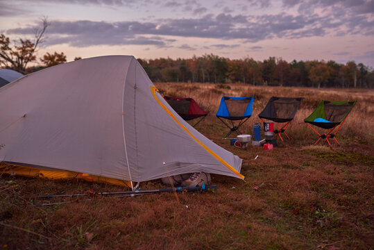 Lit up backpacking tents in field just before sunrise.