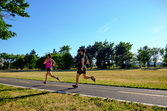 People running through public park along bike path on summer day