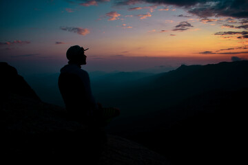 A man starring at sunset on top of a mountain