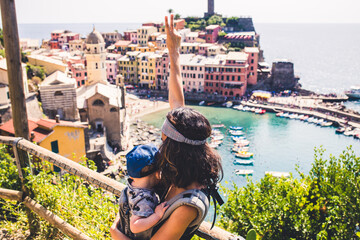 Happy mother with two fingers up while carrying her baby