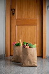 Food shopping bags stand at the door of the house or apartment. Vegetables and fruits delivery during quarantine and self-isolation.
