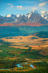 Naklejka premium A picturesque valley with forests and a river against the backdrop of snow-capped mountains.