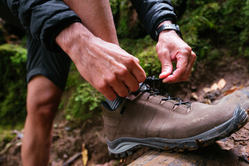Close up young man tying her shoes while trekking