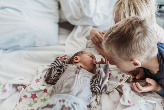 Newborn baby boy meeting big brothers for the first time in hospital
