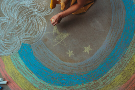 child with sidewalk chalk and rainbow