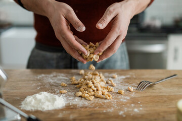 Masculine hands tossing and sprinkling flour on homemade pasta.