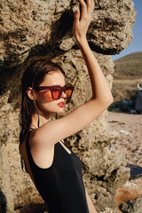 woman in black swimsuit sunglasses rocks posing summer luxury