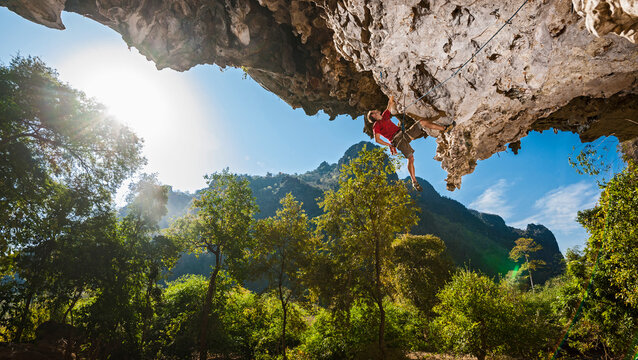 Man climbing on overhanging limestone cliff in Laos