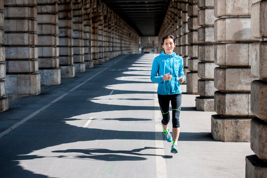 Woman running underneath a Metro viaduct in Paris