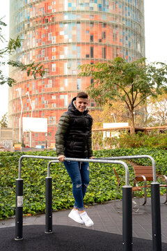 Young guy joining parallel bars outdoors while looking camera outdoors