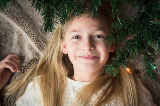 Teen/Tween Girl Lying on Blanket Underneath Christmas Tree Branches