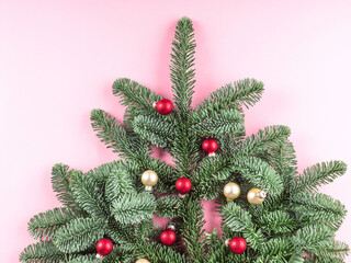 Christmas tree spruce branch decorated with red baubles on pink