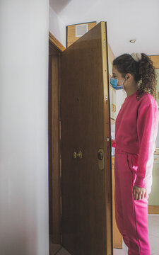 woman opening the door taking an order with a mask and pink tracksuit