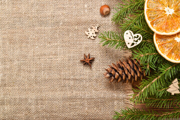 New Year's eco-composition with fir branches, dried oranges, nuts and cinnamon sticks, lying on natural fabric. A mock-up of a Christmas greeting. Copy space. Flat lay, top view.
