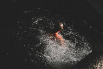 Blonde Boy Emerges From Dark Water Surrounded by Bubbles