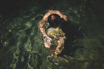 Boy Carries a Stone Submerged Under Rippled Water