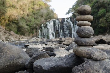 Rock totem made in front of a beautiful blurred waterfall in the background.