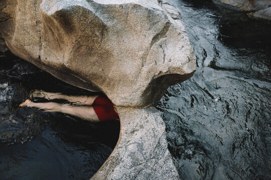 Woman in Red Swims Through a Stone Passage