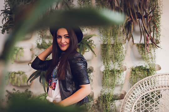 Woman wearing a leather jacket and black hat looking at the camera.