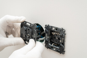 An electrician is installing multifunction outlet with internet connection, tv and electric socket...