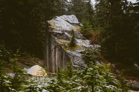 A yellow tent in forest surrounded by towering boulders and trees