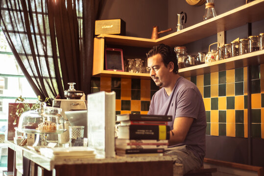 Barista at colourful cafe serving behind counter