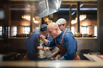 Man trying dish near cooks