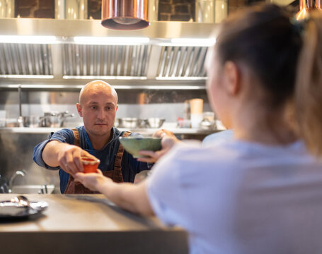 Cook giving food to waitress