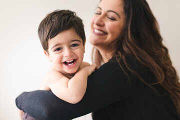 Smiling mom and son being playful, son looking at camera.
