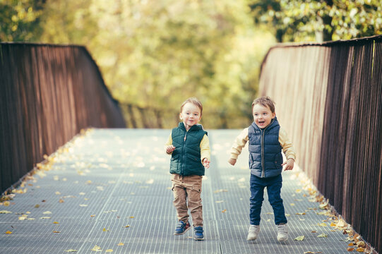 Adorable happy twin boys having fun and jumping in autumn nature