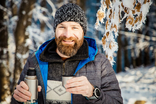 man drinking hot tea in winter forest