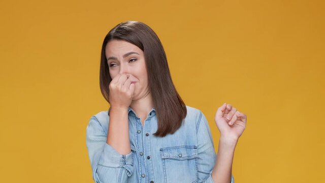 Lady bad smell cover nose empty brown mustard color background isolated