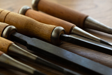 Wood carving chisels, in various sizes, on a old workbench. Shallow depth of field.