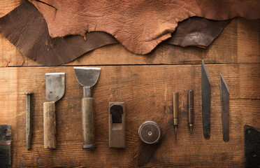Leather craft or leather working. Leather working tools and cut out pieces of　brown leather on leather craftman's work desk .