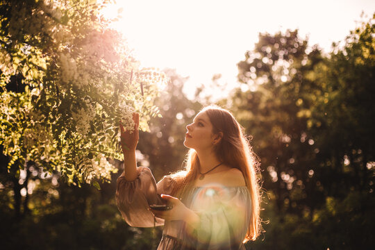 Teenage girl touching flowering branch in park during summer