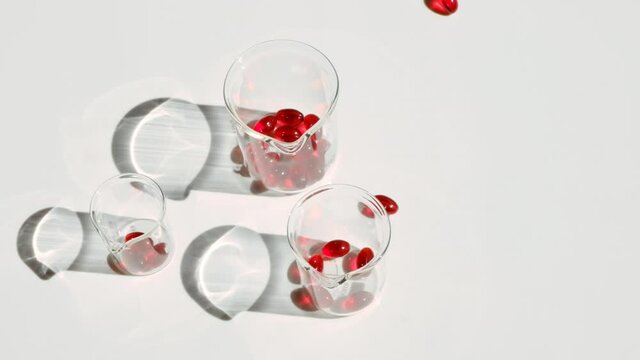Krill oil gelatin capsules in laboratory transparent flasks on a white background.Flying capsules red krill oil.omega fatty acids.Natural supplements and vitamin