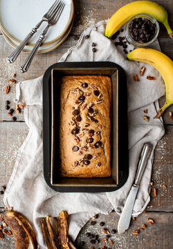 Overhead view of freshly baked banana bread on wooden background.