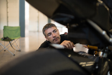 Concentrated man inspecting motorcycle in garage