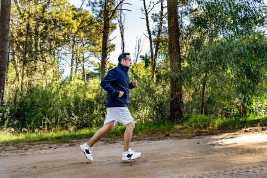 A man running up a trail in the forest in the afternoon