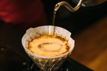 Pouring water in coffee filter at cafe
