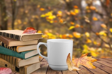 Naklejka na ściany i meble Tea cup with bright fallen leaves and books in the garden. autumn seasonal composition.