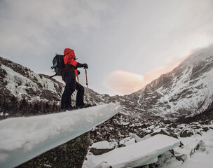 Man on snowshoes stands on frozen ice block in winter, Katahdin Maine